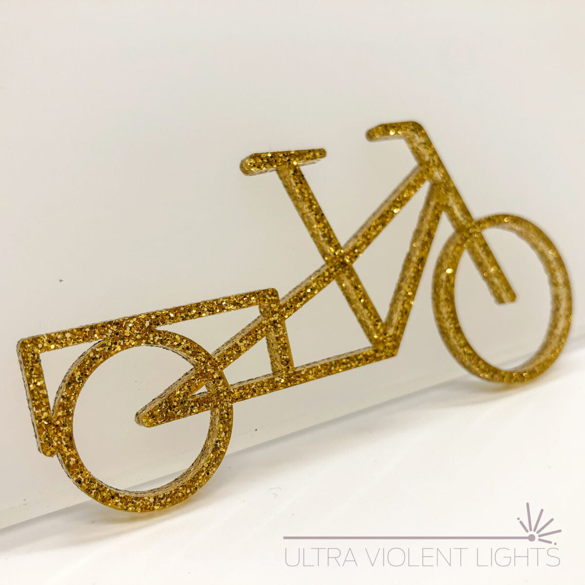 A longtail bike figure in gold acrylic