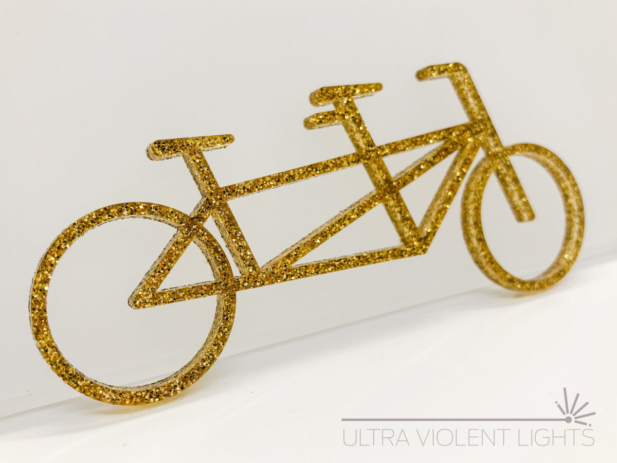 A tandem bike figure in gold acrylic
