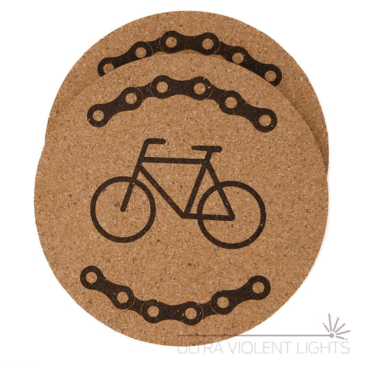 Two cork coasters engraved with bike chains and a bike