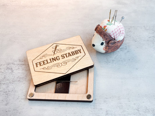 An open needle minder engraved with “feeling stabby”