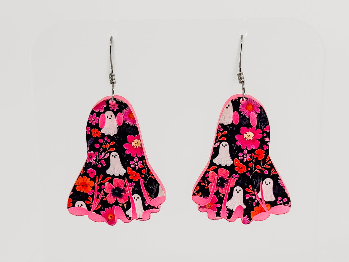 A pair of dangling earrings shaped like ghosts, featuring a black background with a pink, red, and orange floral pattern and small white ghost illustrations, shown against a light gray background.