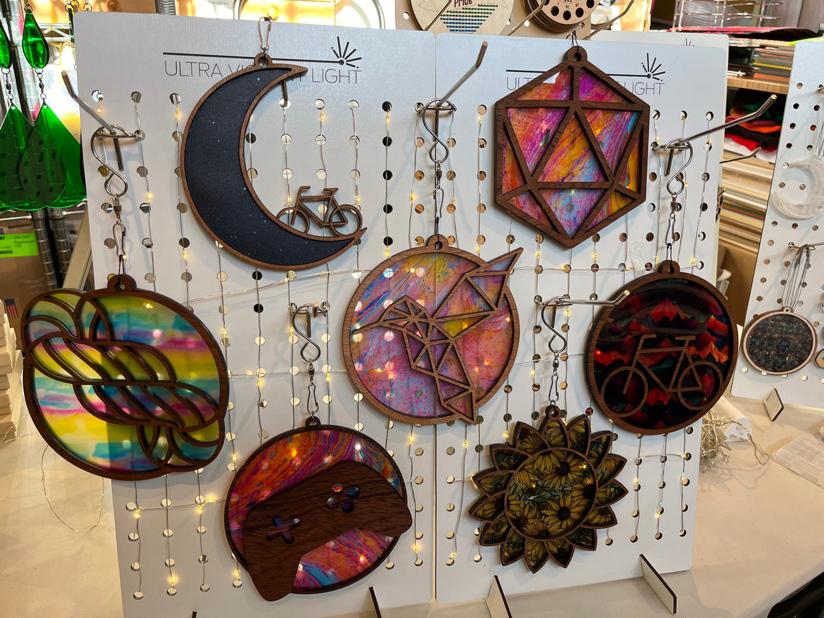 Handmade round birchwood bicycle suncatcher with laser-cut bike silhouette and colorful acrylic backing, hanging on silver chain