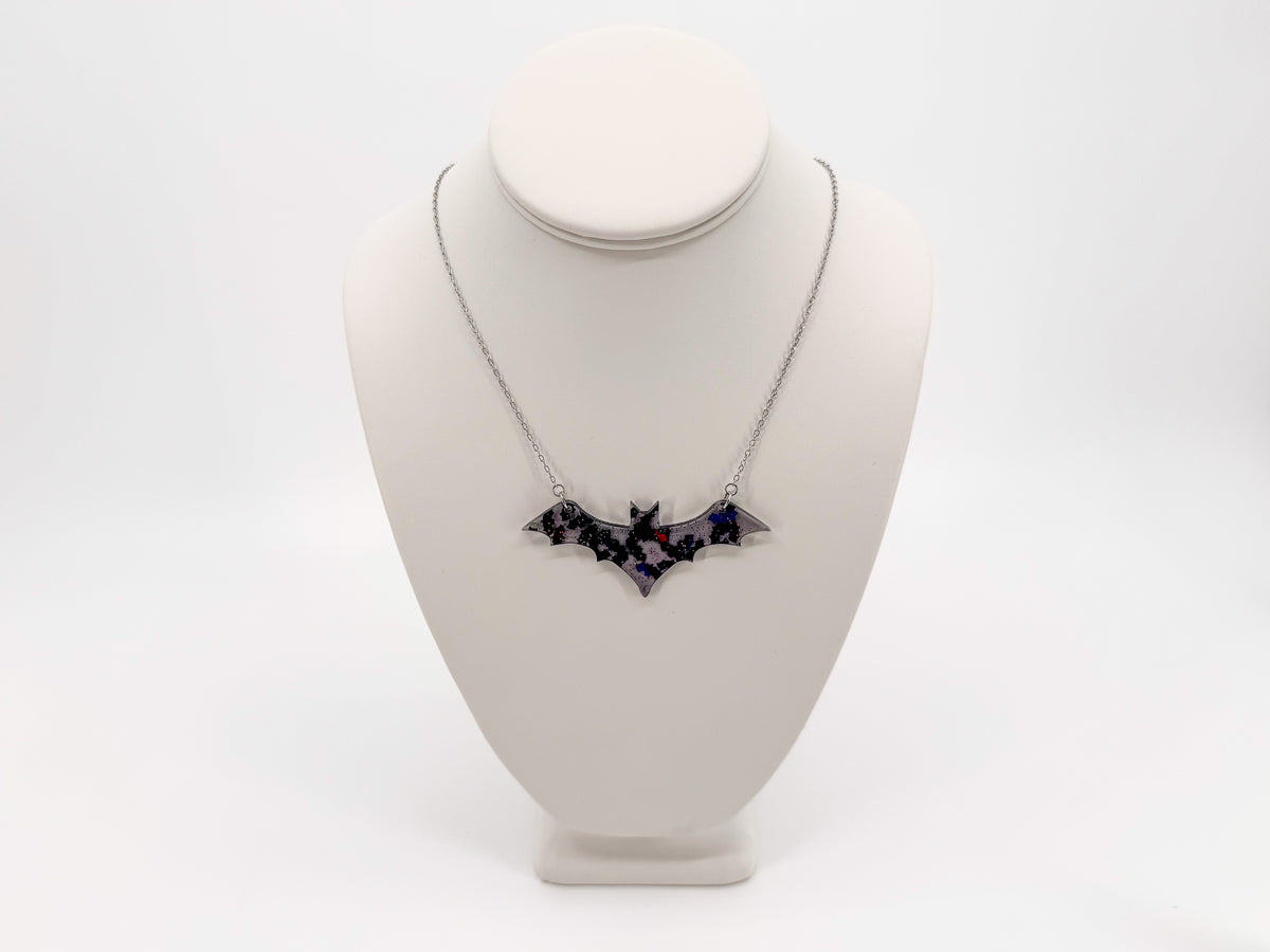 Smoke gray acrylic bat necklace with reflective iridescent bats and a silver-tone chain shown on a white display bust.