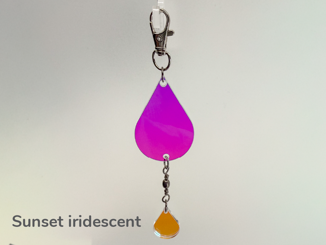 Iridescent purple/pink/orange color-changing teardrop-shaped small sun catcher / keychain on a white background