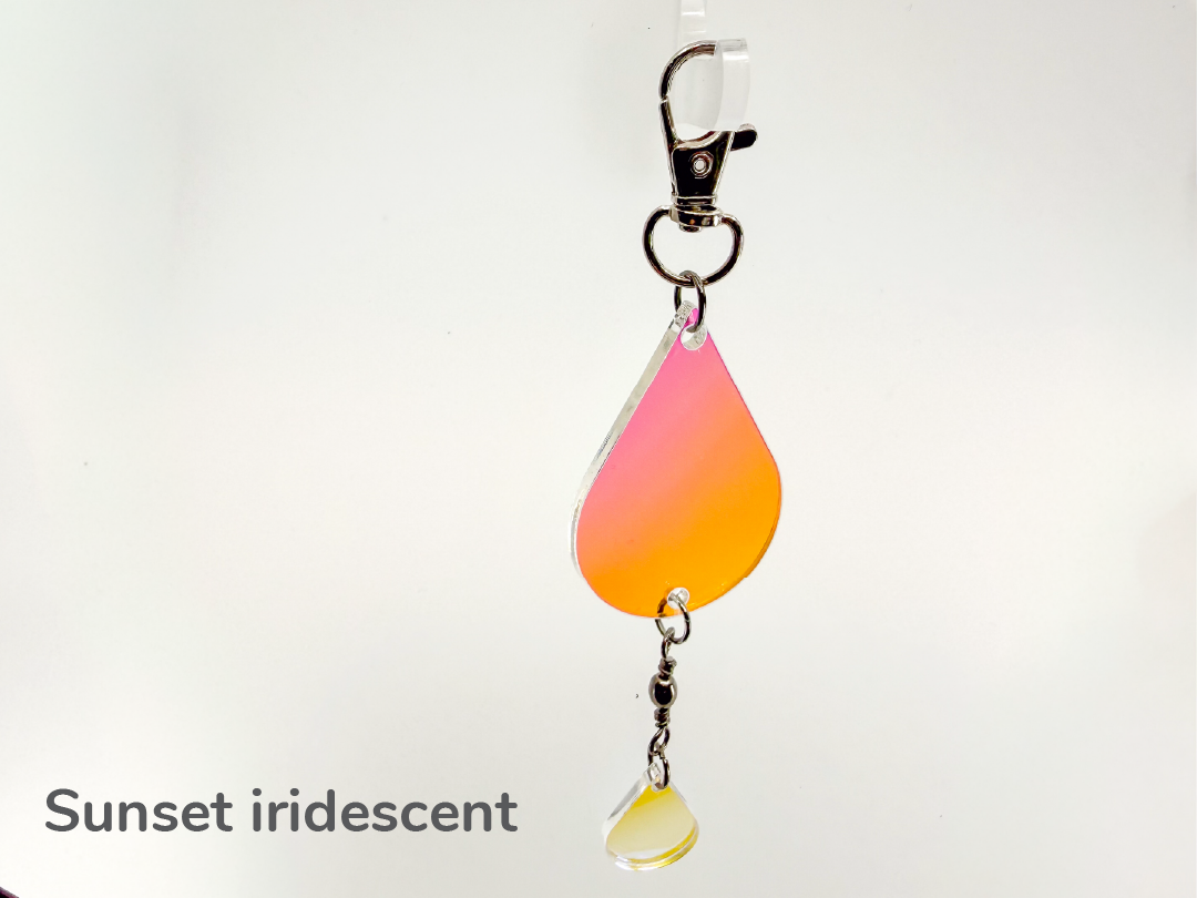 Iridescent purple/pink/orange color-changing teardrop-shaped small sun catcher / keychain on a white background