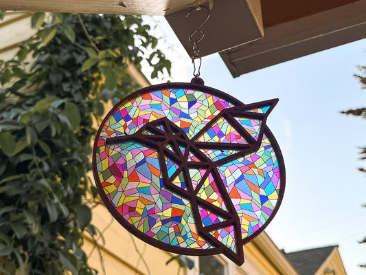 Handmade round birchwood hummingbird suncatcher with colorful stained-glass mosaic acrylic backing and laser-cut hummingbird silhouette, front view on white background with silver chain