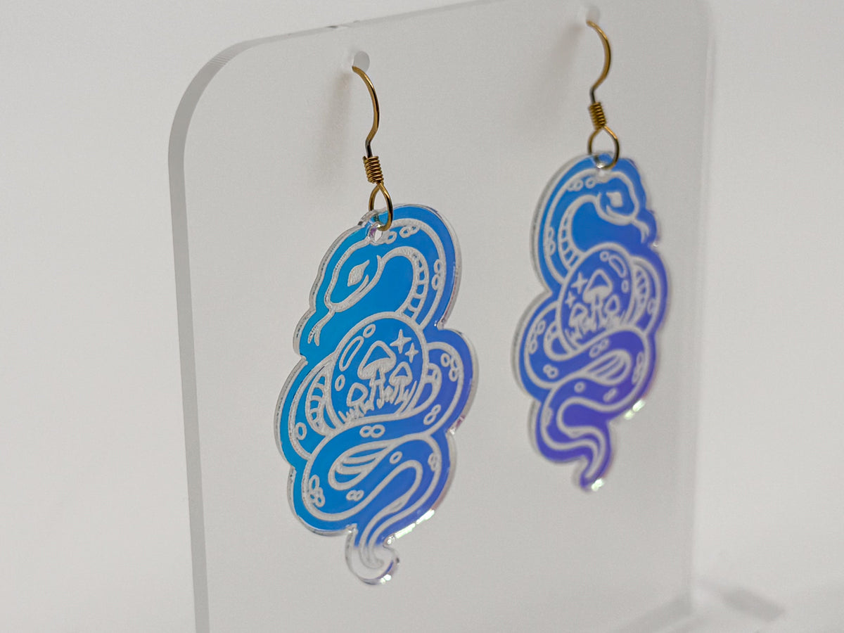 Iridescent snake earrings are displayed on a clear acrylic stand. The stand and earrings are rotating to see all sides.