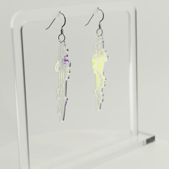 Iridescent sword earrings are displayed on a clear acrylic stand. The stand and earrings are rotating to see all sides.