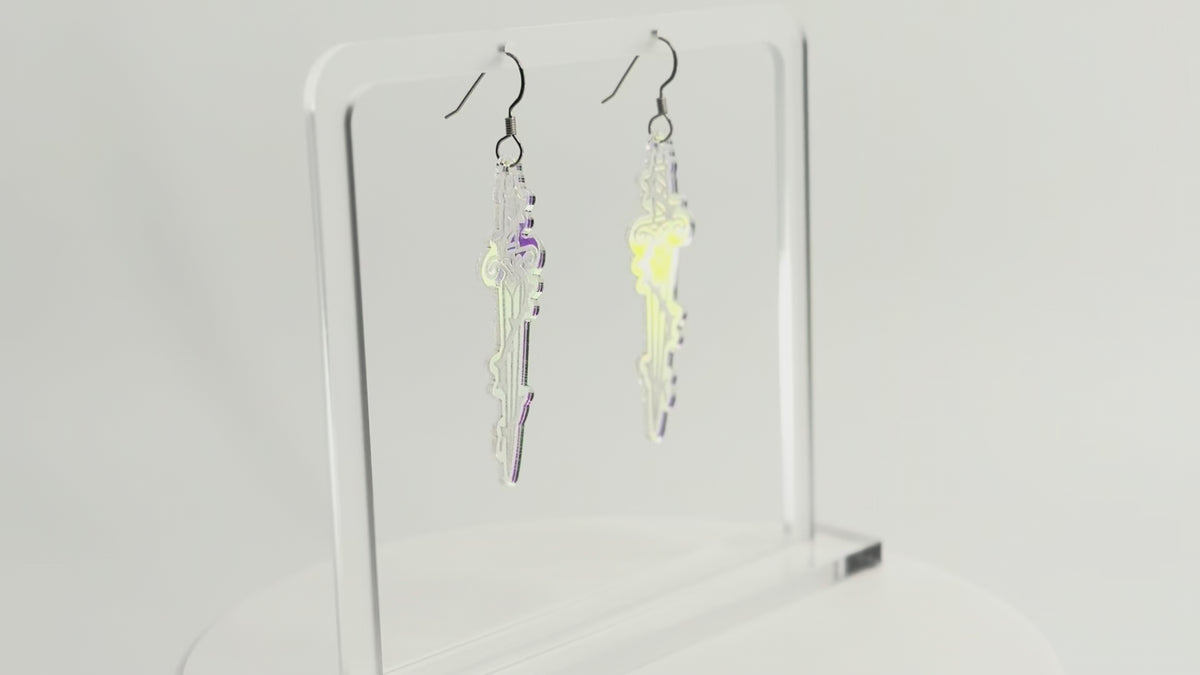 Iridescent sword earrings are displayed on a clear acrylic stand. The stand and earrings are rotating to see all sides.