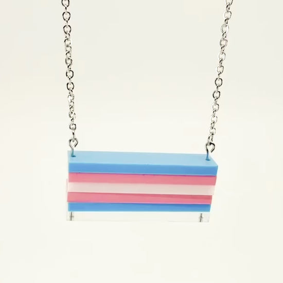 A trans pride flag necklace, shown moving around with a white background.