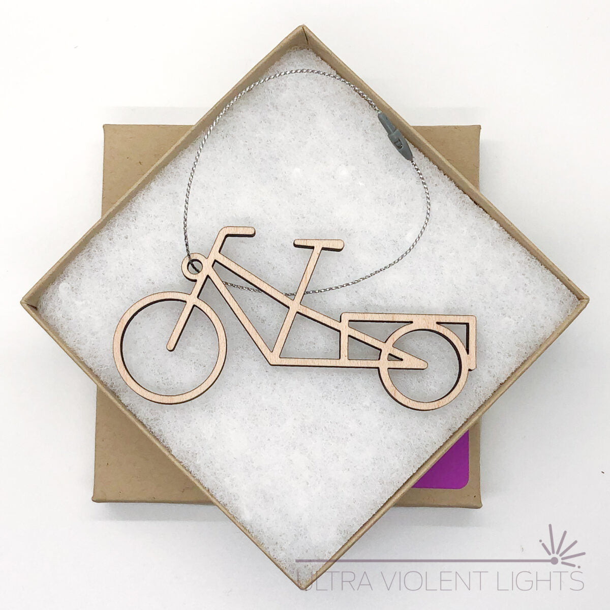 A wooden longtail bike ornament in a square kraft box on a white background