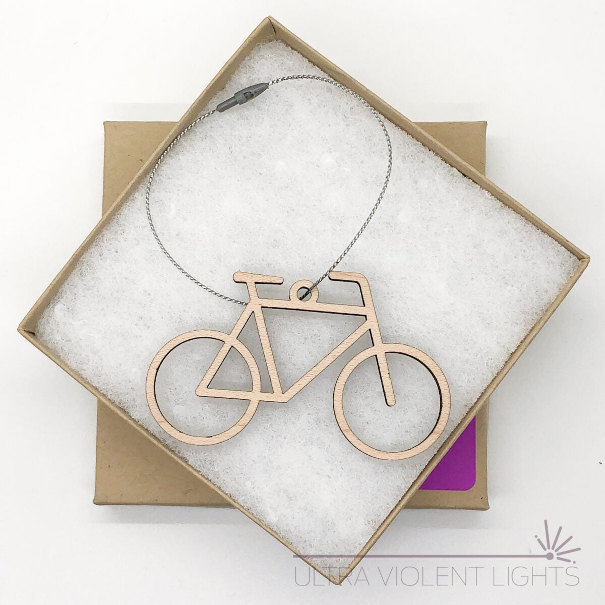 A wooden bike ornament in a square kraft box on a white background