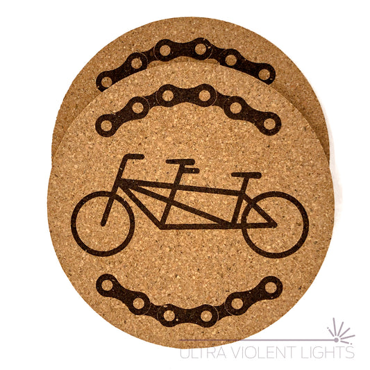 Two cork coasters engraved with bike chains and a tandem bike