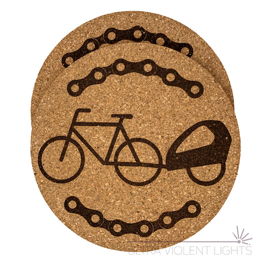 Two cork coasters engraved with bike chains and a bike with a trailer
