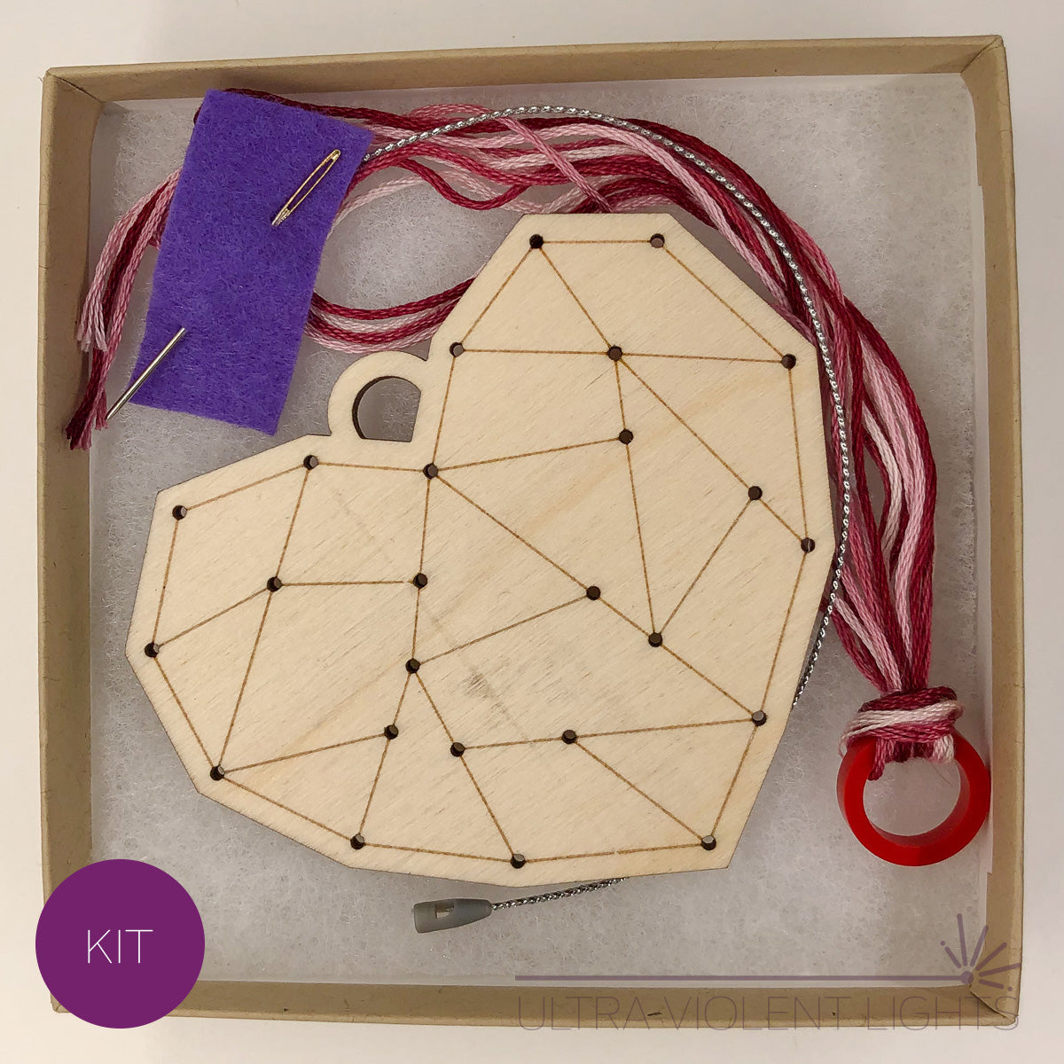 A heart wooden embroidery kit with floss and a needle in a box