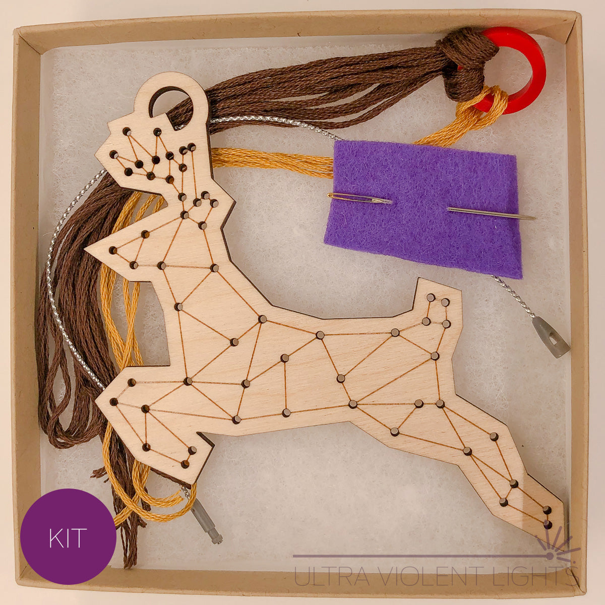 A reindeer wooden embroidery kit with floss and a needle in a box