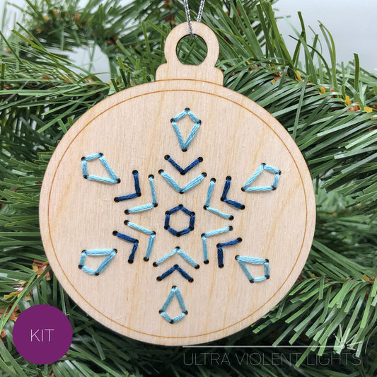 Snowflake embroidered wood ornament on greenery