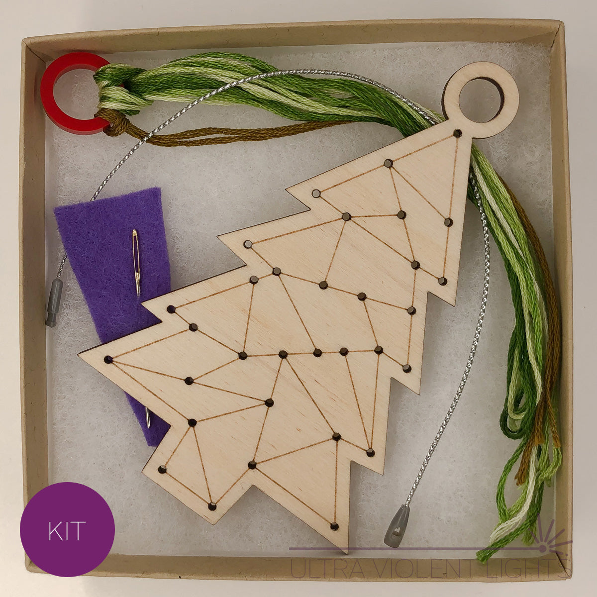 A triangle tree wooden embroidery kit with floss and a needle in a box