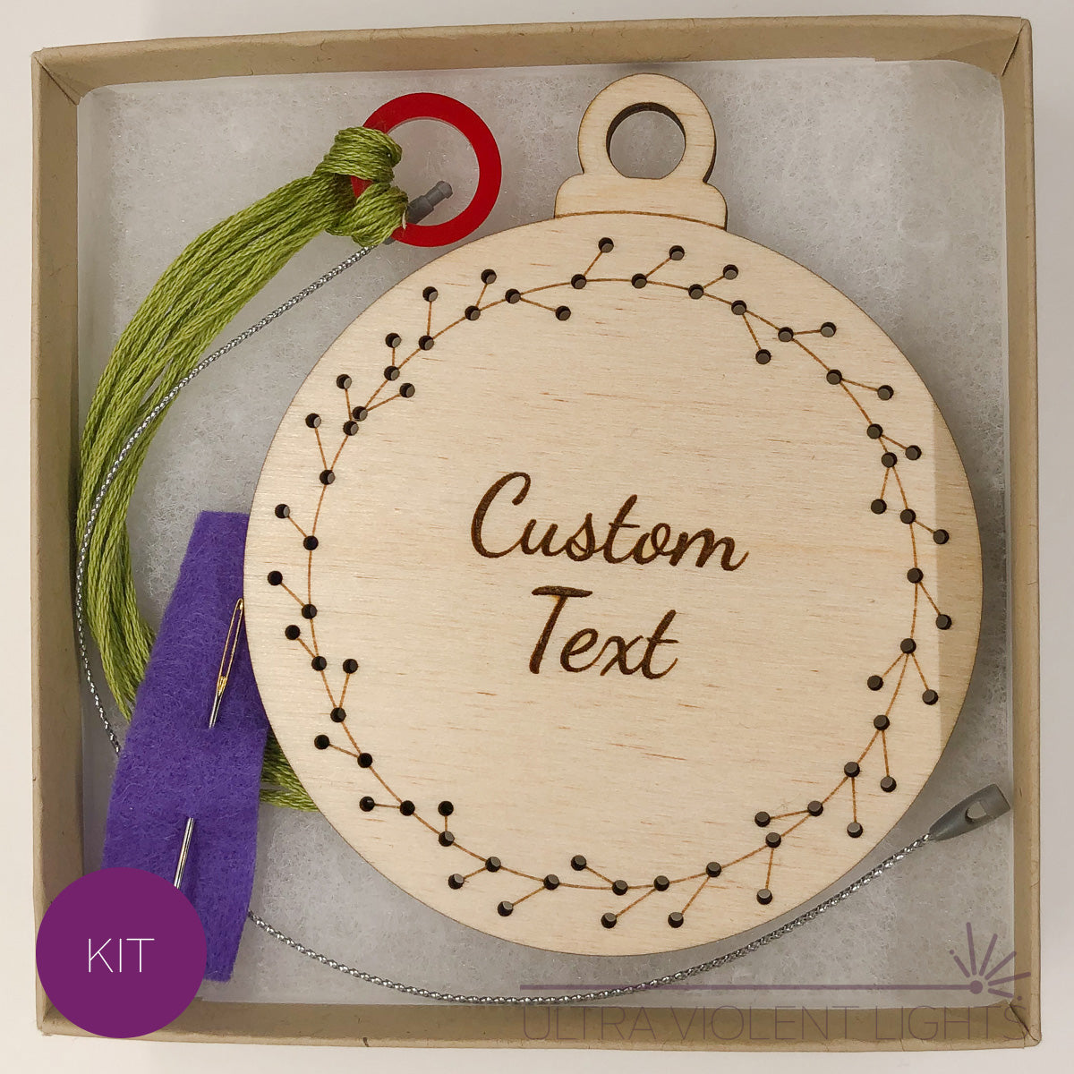A text wreath wooden embroidery kit with floss and a needle in a box